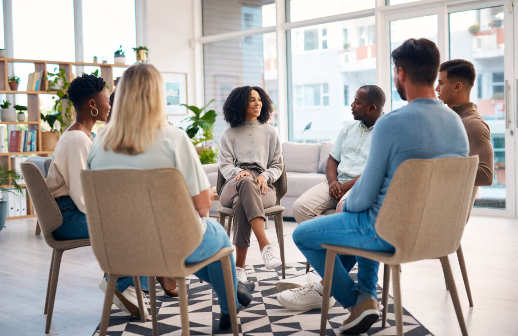 A group of people sitting on chairs in a circle are having a consulting session.